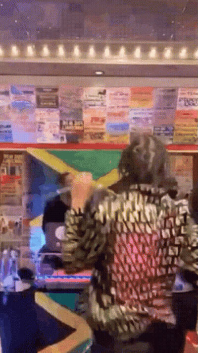 A Woman In A Leopard Print Shirt Is Standing In Front Of A Lottery Machine Holding A Yellow Ribbon . GIF
