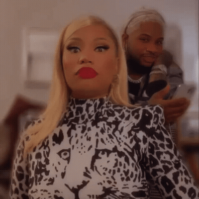A Woman In A Leopard Print Shirt Is Taking A Selfie With A Man Behind Her . GIF