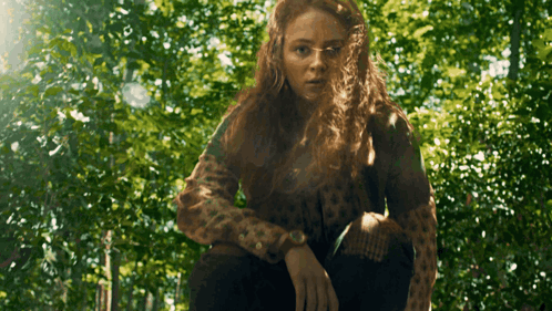A Woman In A Leopard Print Sweater Is Standing In The Woods GIF