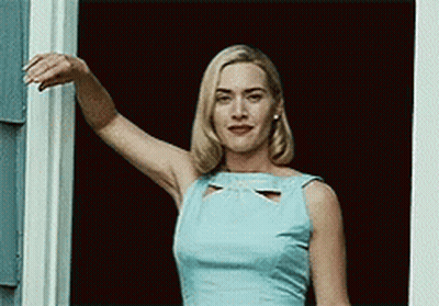 A Woman In A Light Blue Dress Is Standing In Front Of A Window . GIF