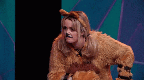 A Woman In A Lion Costume Is Sitting On A Stage With Her Hands On Her Hips . GIF