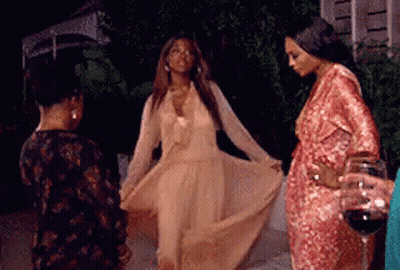A Woman In A Long Dress Is Dancing With Other Women While Holding A Glass Of Wine . GIF