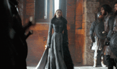 A Woman In A Long Gray Dress Is Standing In Front Of A Group Of Soldiers GIF