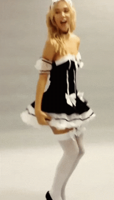 A Woman In A Maid Costume Is Dancing In Front Of A White Wall GIF