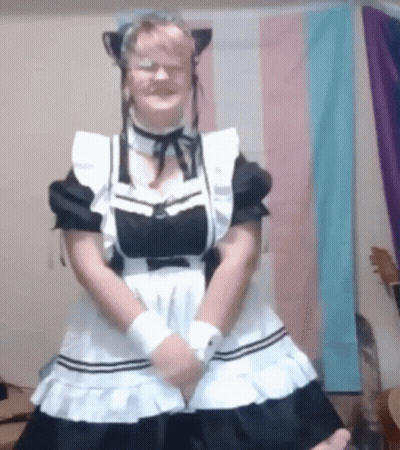 A Woman In A Maid Costume Is Standing In Front Of A Flag . GIF