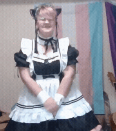 A Woman In A Maid Costume Is Standing In Front Of A Flag . GIF