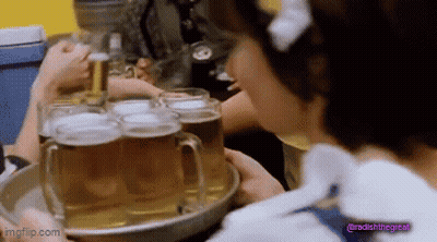 A Woman In A Maid Outfit Is Holding A Tray Of Beer GIF