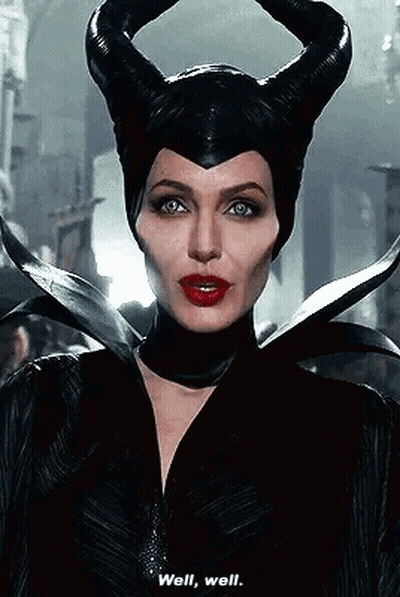 A Woman In A Maleficent Costume With Horns On Her Head Is Talking To Someone . GIF