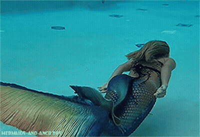 A Woman In A Mermaid Costume Is Swimming In The Water GIF