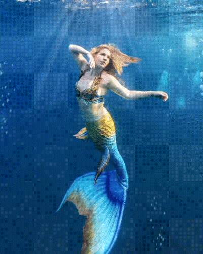 A Woman In A Mermaid Costume Is Swimming In The Water GIF