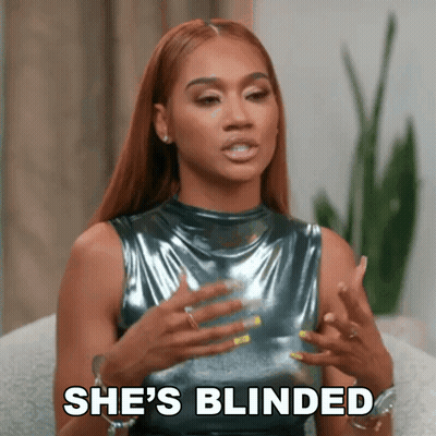 A Woman In A Metallic Top Is Sitting On A Couch And Talking To Someone . GIF