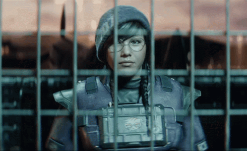 A Woman In A Military Uniform Is Behind Bars And Has A Badge On Her Chest That Says ' Ec ' GIF