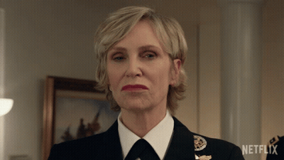 A Woman In A Military Uniform Is Standing In Front Of A Netflix Logo GIF