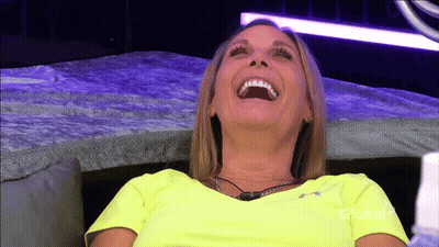 A Woman In A Neon Yellow Shirt Is Laughing On A Couch GIF