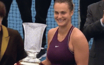 A Woman In A Nike Tank Top Is Holding A Trophy GIF