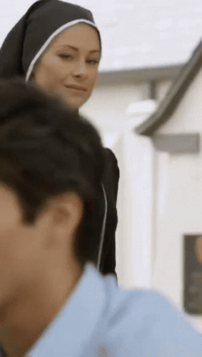 A Woman In A Nun 'S Habit Stands Next To A Man In A Blue Shirt . GIF