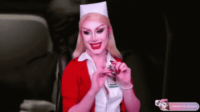 A Woman In A Nurse Costume Is Smiling And Holding A Badge GIF