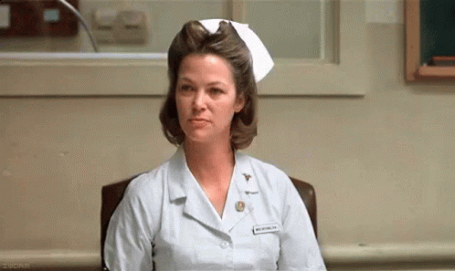 A Woman In A Nurse 'S Uniform Is Sitting In A Chair . GIF