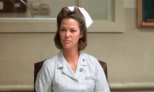 A Woman In A Nurse 'S Uniform Is Sitting In A Chair . GIF