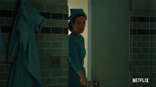 A Woman In A Nurse 'S Uniform Is Standing In A Doorway With A Netflix Logo Behind Her GIF