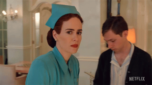 A Woman In A Nurse 'S Uniform Is Standing Next To A Man With A Netflix Logo On His Shirt GIF