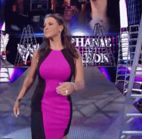 A Woman In A Pink And Black Dress Is Walking Down A Ramp In Front Of A Ladder . GIF