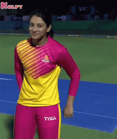 A Woman In A Pink And Yellow Striped Shirt And Pink Pants Is Standing On A Track . GIF