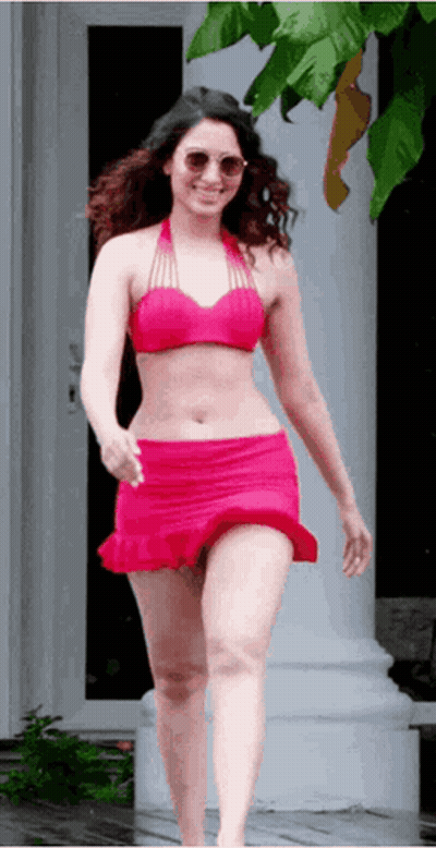 A Woman In A Pink Bikini And Red Skirt Is Walking Down A Sidewalk . GIF