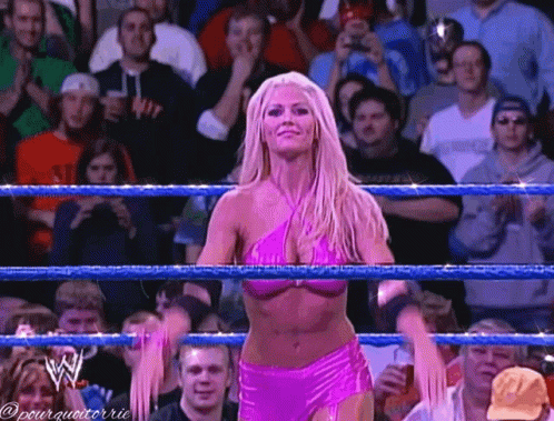 A Woman In A Pink Bikini Is In A Wrestling Ring With A Crowd Watching GIF
