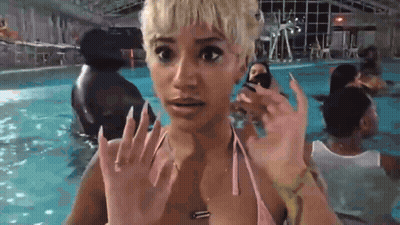 A Woman In A Pink Bikini Is Standing In A Swimming Pool With A Surprised Look On Her Face . GIF