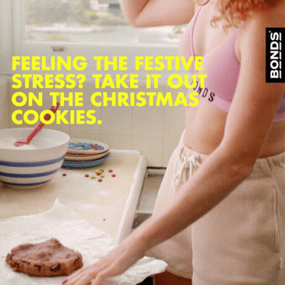 A Woman In A Pink Bra And Shorts Is Baking Cookies With The Words Feeling The Festive Stress Take It Out On The Christma GIF