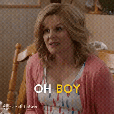 A Woman In A Pink Cardigan Is Sitting At A Table And Says `` Oh Boy '' . GIF