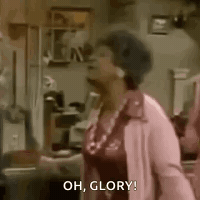 A Woman In A Pink Coat Is Standing In A Living Room . GIF