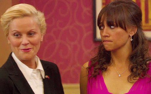A Woman In A Pink Dress And A Woman In A Suit Are Standing Next To Each Other GIF