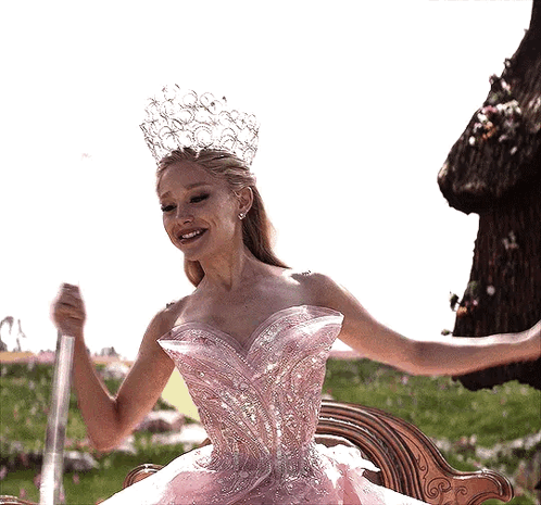 A Woman In A Pink Dress And Crown Is Holding A Wand GIF