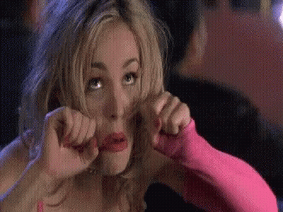 A Woman In A Pink Dress And Pink Gloves Is Making A Face . GIF