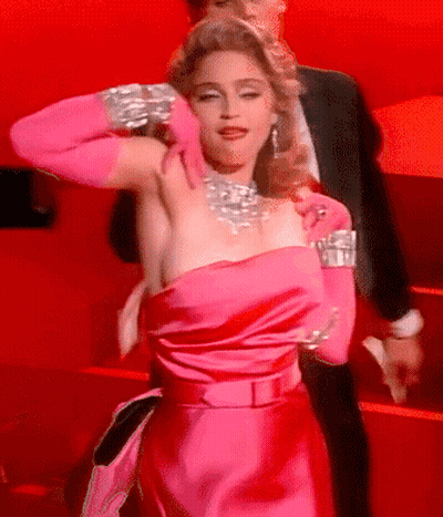 A Woman In A Pink Dress And Pink Gloves Is Standing Next To A Man In A Suit GIF