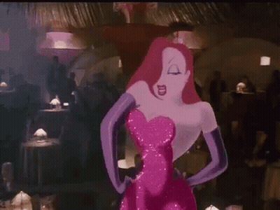 A Woman In A Pink Dress And Purple Gloves Is Standing In A Crowded Room . GIF