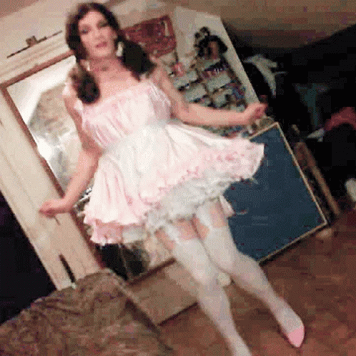 A Woman In A Pink Dress And White Stockings Is Dancing In A Living Room GIF