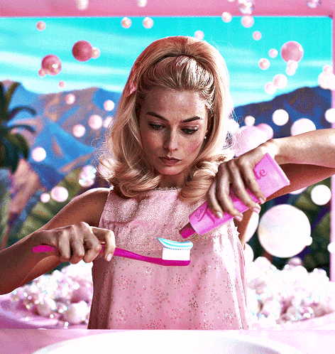 A Woman In A Pink Dress Brushes Her Teeth With A Pink Toothbrush GIF