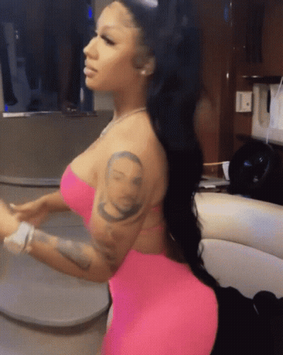 A Woman In A Pink Dress Has A Tattoo On Her Arm Of A Man 'S Face GIF
