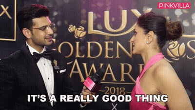 A Woman In A Pink Dress Is Being Interviewed By A Man In A Tuxedo At The Lux Golden Awards 2018 GIF