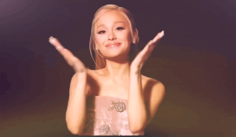 A Woman In A Pink Dress Is Clapping Her Hands In The Air GIF