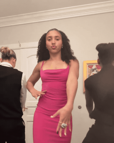 A Woman In A Pink Dress Is Dancing In Front Of A Door GIF