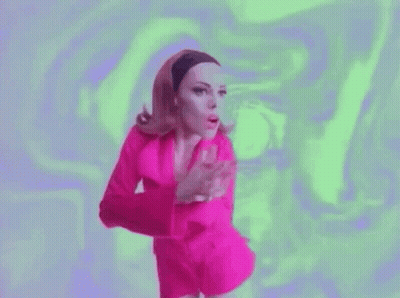 A Woman In A Pink Dress Is Dancing In Front Of A Green Background . GIF