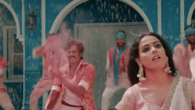 A Woman In A Pink Dress Is Dancing With A Group Of Men GIF