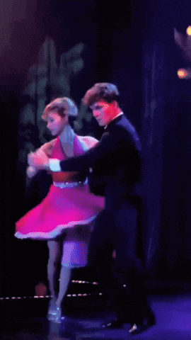 A Woman In A Pink Dress Is Dancing With A Man In A Suit GIF