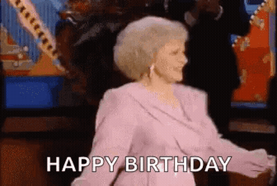 A Woman In A Pink Dress Is Dancing With The Words `` Happy Birthday '' Behind Her . GIF