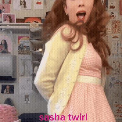 A Woman In A Pink Dress Is Dancing With The Words Sasha Twirl Written Below Her GIF