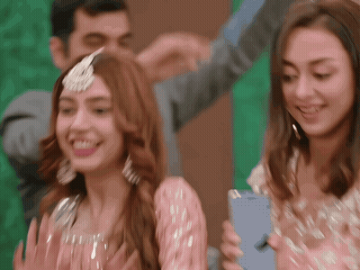 A Woman In A Pink Dress Is Holding A Blue Iphone GIF